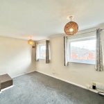 Bright, carpeted room with windows and ceiling lights.