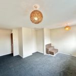 Empty carpeted room with light fixtures and small steps.