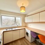 Modern kitchen with washing machine and colourful chairs