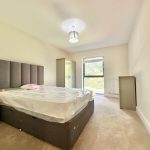 Bright bedroom with double bed and large window.