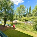 Canal boats moored along a scenic, tree-lined river.
