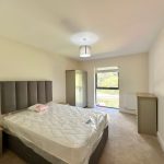 Modern bedroom with double bed and window view.
