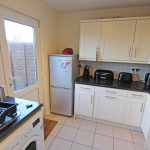 Modern kitchen with white cabinets and appliances.