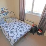 Small bedroom with metal bed and window.