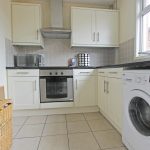 Modern kitchen with appliances and tiled floor.
