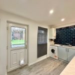 Modern kitchen with garden view through door.