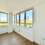 Bright empty room with large windows and city view.