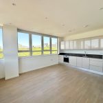 Modern kitchen with large windows and light flooring.
