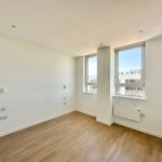 Empty room with large windows, wooden floor.