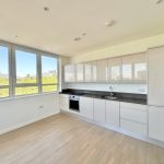 Modern kitchen with large windows and light wood flooring.