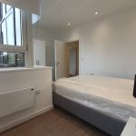 Minimalist modern bedroom with large window and bed.