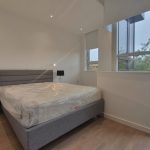 Modern bedroom with large windows and grey bed.