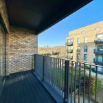 Modern balcony overlooking apartment building and garden.