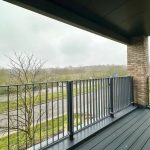 Covered balcony overlooking road and trees on cloudy day.