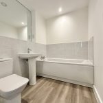 Modern bathroom with bathtub, sink, toilet, towel radiator.