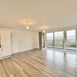 Empty modern flat with balcony and large windows.