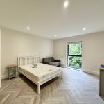 Bright bedroom with bed, sofa, and window view.