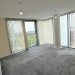 Bright empty room with large windows and blinds.