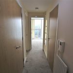 Well-lit hallway with carpet and doors.