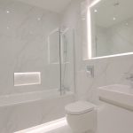 Modern marble bathroom with sleek fittings and lighting.