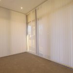 Empty room with vertical blinds and carpet.