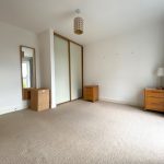 Minimalist bedroom with wardrobe and bedside tables.