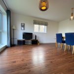 Spacious living room with wooden flooring and furniture.