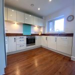 Modern kitchen with white cabinets and wooden floor.