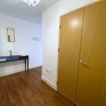 Hallway with wooden floor, table and mirror.