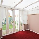 Bright conservatory interior with red carpet flooring.