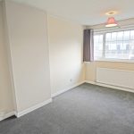 Empty room with grey carpet and window.