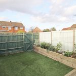 Small garden with artificial grass and raised beds.