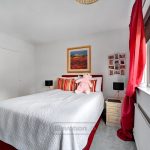 Cosy bedroom with pink teddy and red curtains.