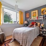 Cosy bedroom with grey wall and yellow curtains.