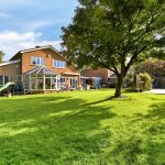 Spacious garden with house and conservatory view.