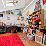 Art studio with paintings, books, and colourful decor.