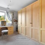Spacious bedroom with wooden wardrobes and dressing table.