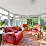 Bright conservatory with red furniture and garden view