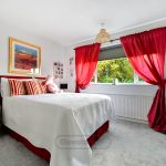 Cosy bedroom with red curtains and bright decor.