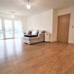 Spacious living room with wooden flooring and sofa.
