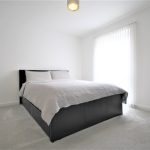 Minimalist bedroom with double bed and natural light.