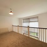 Loft area with carpet, railing, and window.