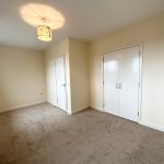 Spacious carpeted room with white wardrobe and light.