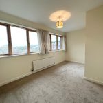 Empty room with windows and beige carpet.