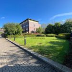 Brick building with landscaped garden and blue sky.