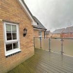 Small balcony with brick wall and cloudy sky.