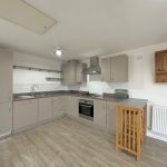 Modern kitchen with grey cabinets and wooden flooring.