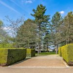 Tree-lined path with neatly trimmed hedges.