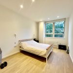Minimalist bedroom with large window and wooden floor.