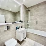 Modern bathroom with grey tiles and white fixtures.